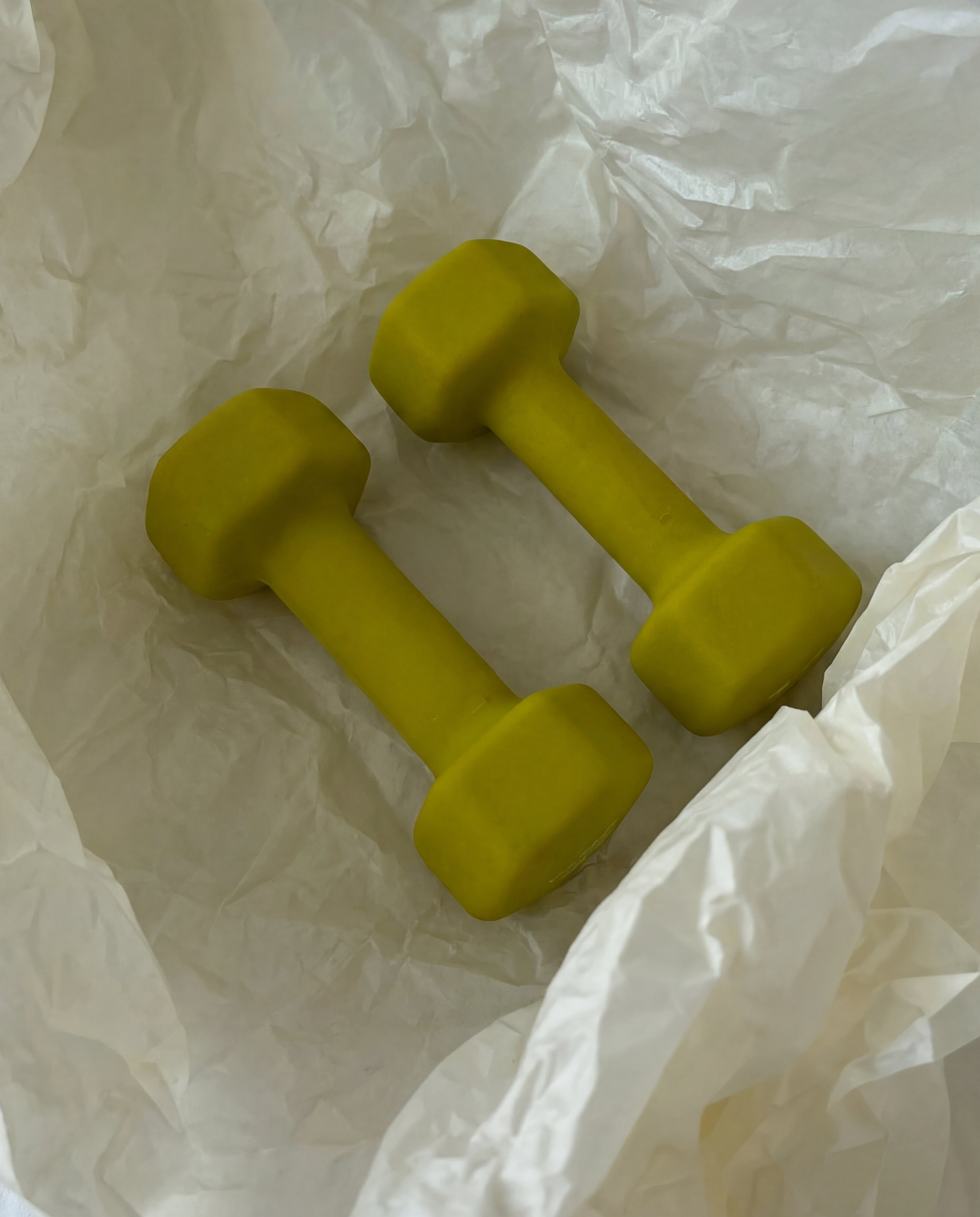 Two green dumbbells on crumpled white paper
