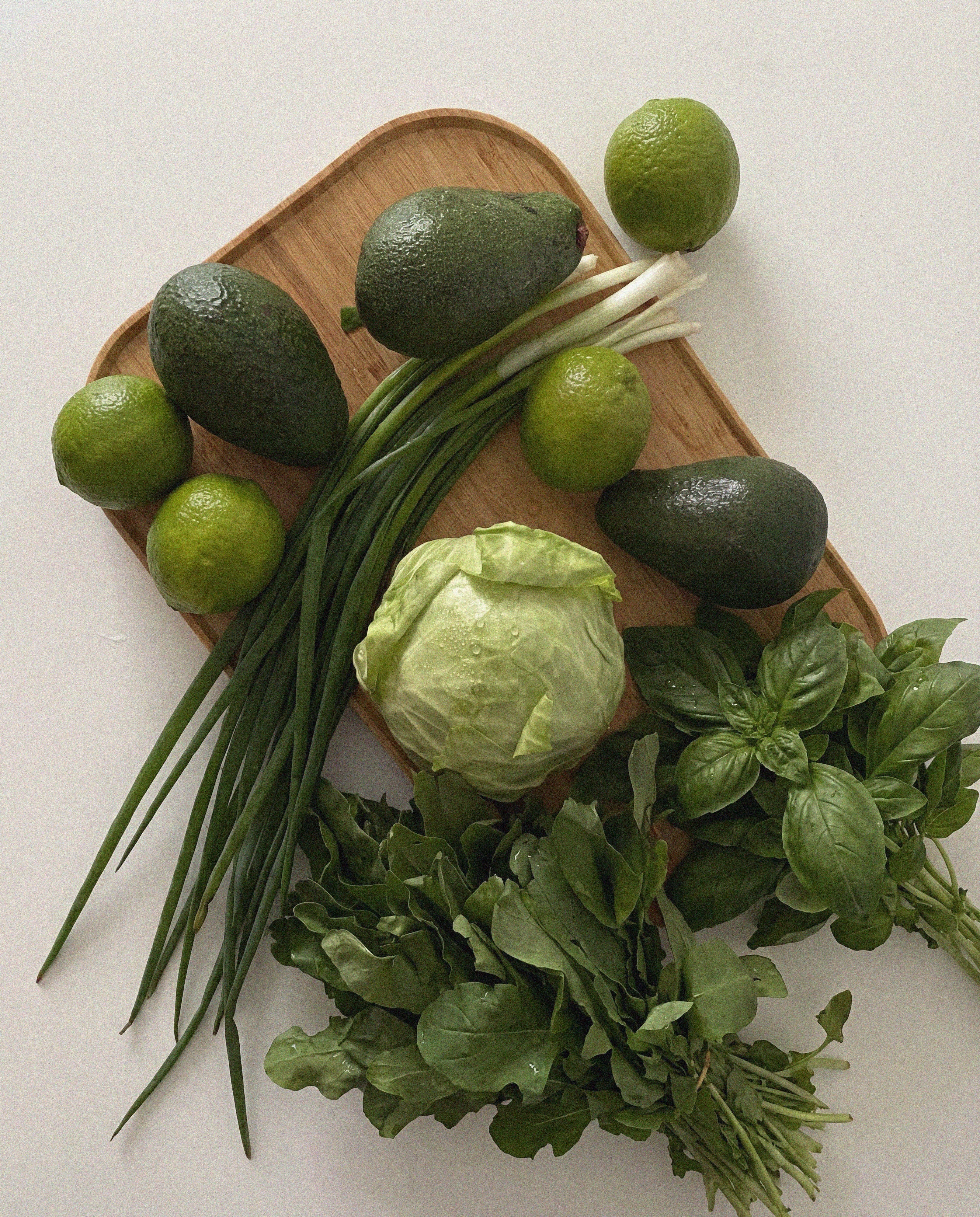Assorted green fruits and vegetables on a wooden cutting board