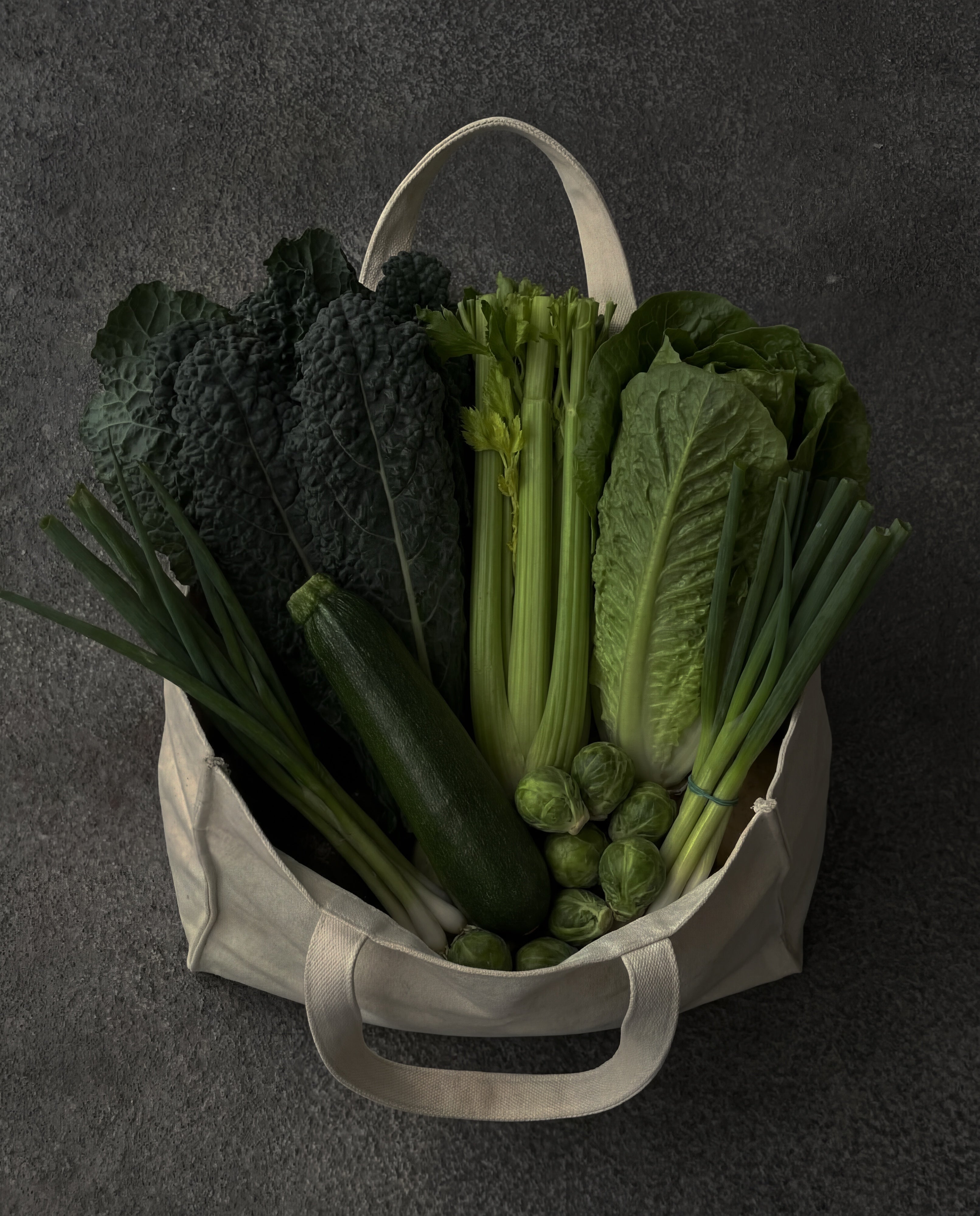 Bag filled with green vegetables on a dark background